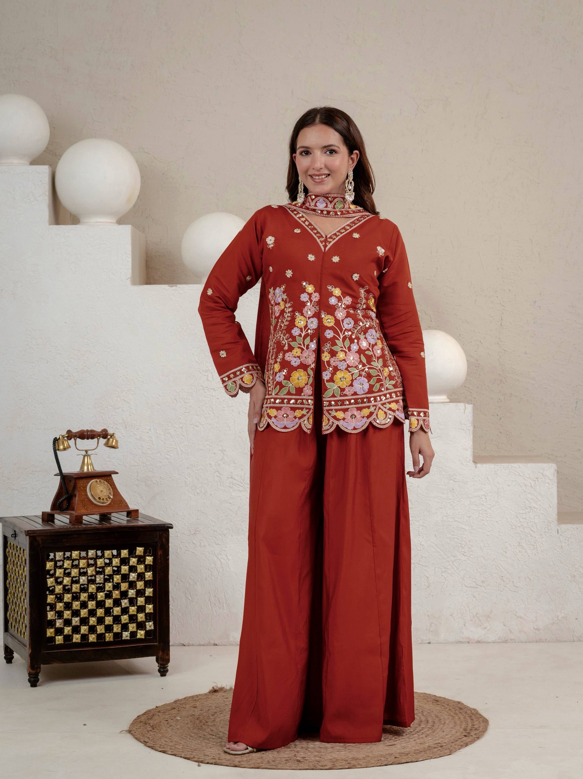 Resplendent Rust Orange Peplum Kurti and Flared Palazzo Suit Set Adorned with Intricate Multicolored Floral Embroidery, Sequin Accents, and Ornate Scalloped Borders